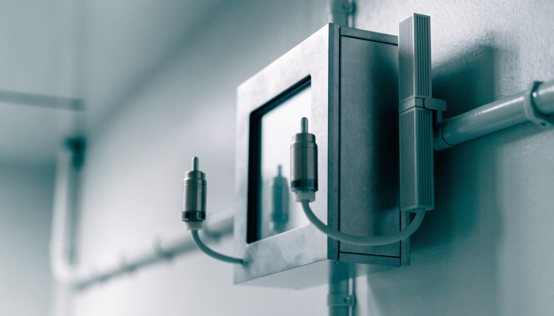 A wall-mounted environmental control unit in a clean utility room, with two sensor probes on short cables and a slim data logger clipped beside it